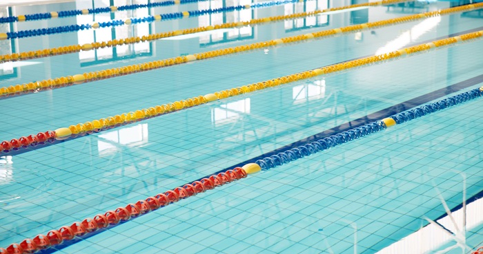 Indoor swimming pool with marked lap lanes and calm blue water inside a public aquatic facility.