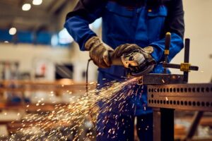 Industrial worker using an angle grinder on metal in an Abbeville manufacturing facility, representing workplace injury and workers’ compensation claims