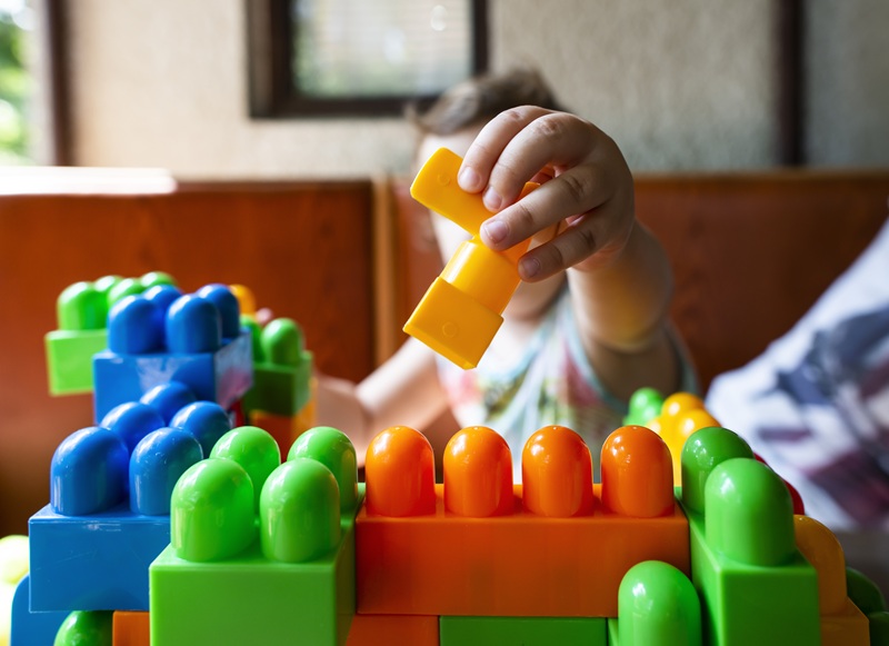 A child is playing with colorful, stackable blocks. Children's toys can be subject to some product defect claims.