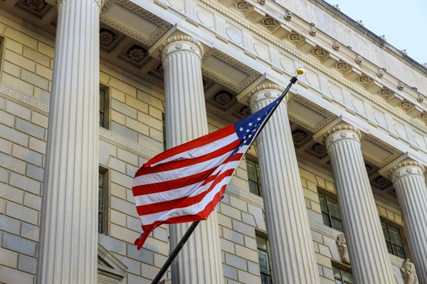 An American flag waving outside of a courthouse.