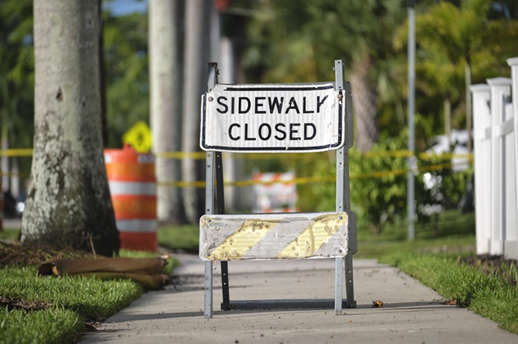 Warning sign that sidewalk is closed at street construction site. Utility work ahead.