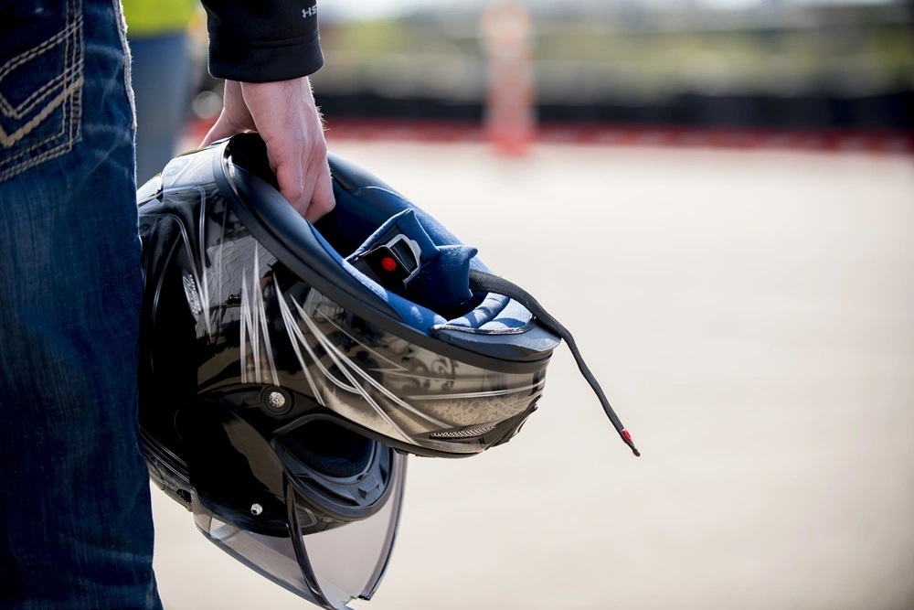 Close up of a biker holding a motorcycle helmet.
