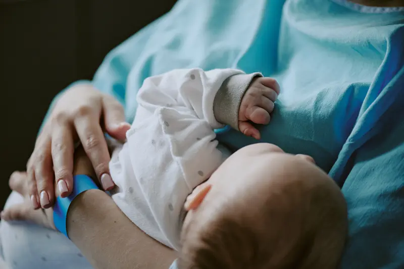 A person in a medical gown holding a newborn