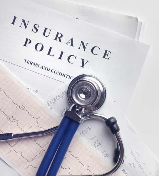 A stethoscope on top of medical documents and an insurance policy report.
