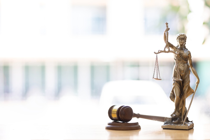 A gavel and Lady Justice on a desk in a sunny office.