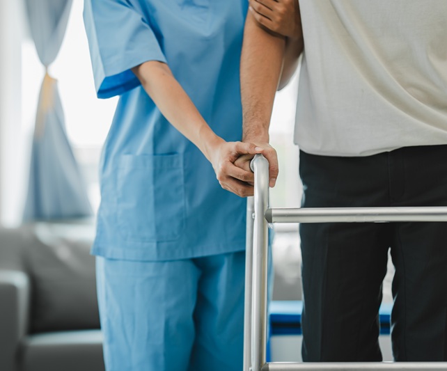 A medical assistant is helping a patient learn how to walk again