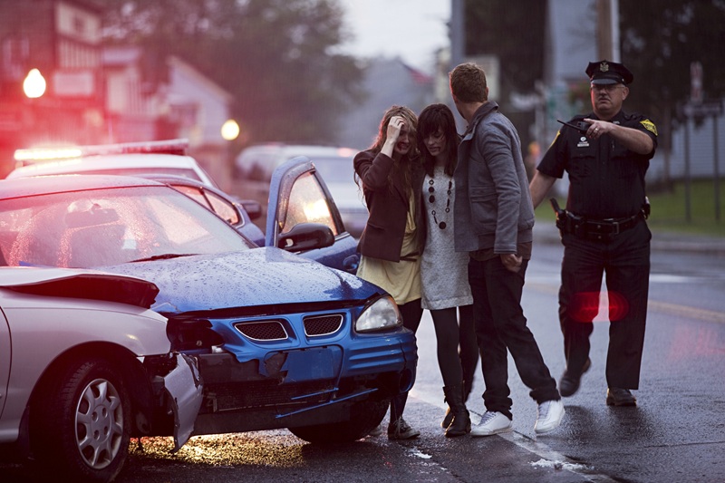 Three people are talking to a police officer after a vehicle collision.