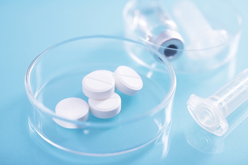 A closeup shot of  white pills in a glass dish at a lab