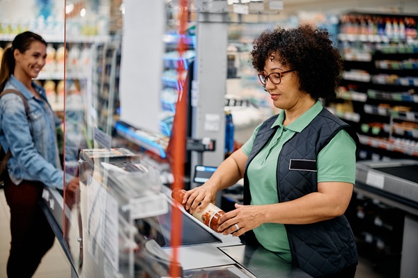 A smiling female cashier at a grocery store